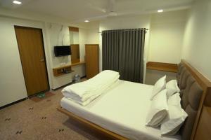艾哈迈达巴德Hotel Shertown的卧室配有一张带白色床单和枕头的大床。