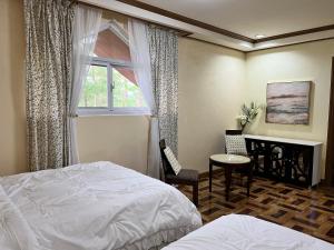 碧瑶CAMPJOHNHAY Forest Estate的一间卧室配有一张床、一张书桌和一个窗户。