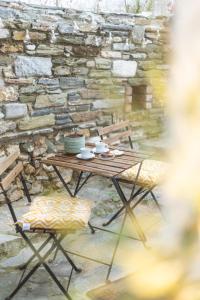 沃洛斯Bardis Hidden Gem的一张木桌、两把椅子和石墙