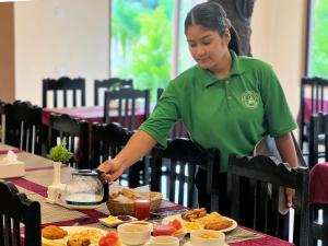 索拉哈Ama Garden Sauraha的穿着绿色衬衫的女人在桌子上准备食物