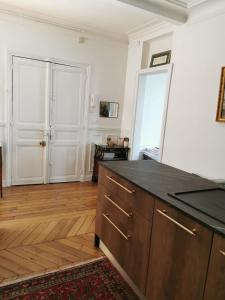 巴黎Home sweet home的厨房铺有木地板,配有黑色台面