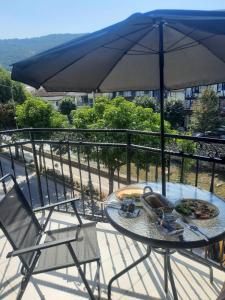 普里兹伦Comfort Hotel Prizren的阳台配有桌椅和遮阳伞