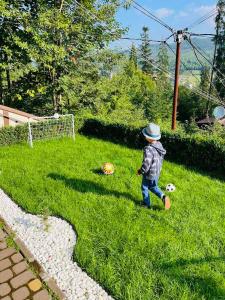 布克维Котедж Chalet Adriana的一个小男孩,带着足球在草地上行走
