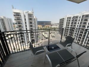 阿布扎比OC Design at Yas Island - Deluxe Apartment的阳台配有两把椅子和一张桌子,部分建筑