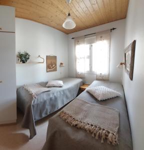 萨利色尔卡Apartment Urupaa的配有白色墙壁和木制天花板的客房内的两张床