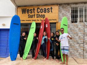 依索安WEST COAST HOSTEL的一群人把冲浪板放在商店前