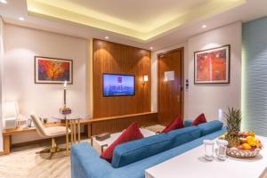 多哈多哈世纪大酒店的客厅配有2张蓝色沙发和电视