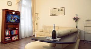 布达佩斯经典中央公寓 的带沙发的客厅和餐桌上的一瓶葡萄酒