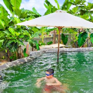 V Village Làng quê Việt的游泳池里的人,带雨伞