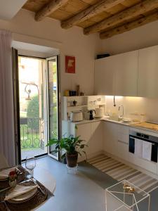 梅纳焦Villa Paola - Holiday Apartment - Menaggio, Lago di Como的一间厨房,配有白色的橱柜和大窗户
