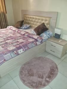 达喀尔Résidence Hadja 01的一间卧室配有一张带脚板和地毯的床