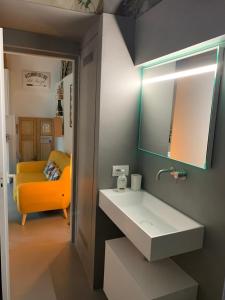 梅纳焦Villa Paola - Holiday Apartment - Menaggio, Lago di Como的一间带水槽和黄色沙发的浴室