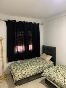 乌季达Appartement cosy et pratique的一间卧室设有两张床和黑色窗帘
