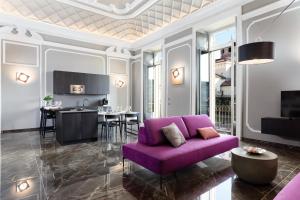 都灵Q71 TIMELESS SUITES的一间带紫色沙发的客厅和一间厨房