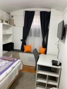 德布勒森Centrum Wellness Hostel的小房间设有床、书桌和窗户