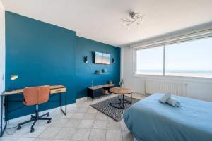 敦刻尔克*Face à la mer* Malo-les-bains的一间卧室设有蓝色的墙壁、一张桌子和一张床