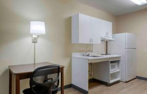 纽波特纽斯Extended Stay America Select Suites - Newport News - Oyster Point的一间带书桌和白色冰箱的小厨房