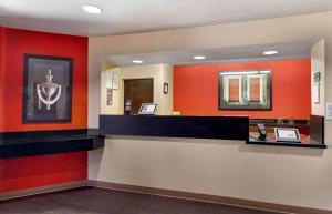 长滩美国延住酒店（洛杉矶长滩机场店）的一间设有红色墙壁和前台柜台的等候室