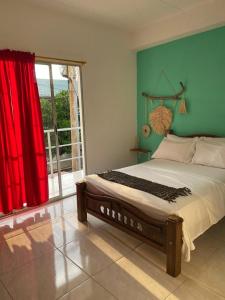 帕洛米诺Casa Guiwa Hostel的一间卧室配有一张带红色窗帘的大床