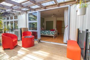 旺阿雷Waimoana Garden Accommodation的带红色椅子的屏风门廊和一间卧室