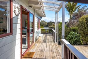 欧尼坦基Onetangi Beach Retreat - Waiheke Holiday Home的一个带木甲板的房子的门廊