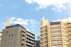福冈HOTEL Third Place Hakata的蓝色天空前两栋高公寓楼