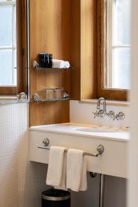 悉尼Sydney Harbour Hotel的浴室配有盥洗盆、镜子和毛巾