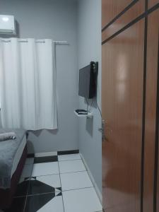 马拉巴Ap. 2 quartos próx. Aeroporto的一间设有一张床的房间和一扇带电视的门