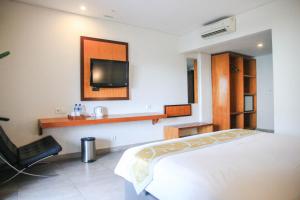 库塔德库塔酒店的卧室配有一张床,墙上配有电视。