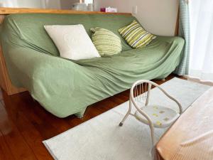 名户憩いの場　ただいま〜的客房内的一张带枕头和椅子的绿床