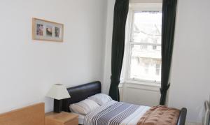 爱丁堡爱丁堡皇家大道公寓的卧室在窗户前配有一张床