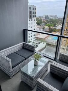 卧龙岗Designer 1 BR Apt in Wollongong with Ocean Views的阳台配有桌子、藤椅和大窗户。