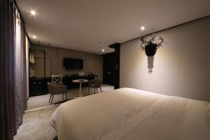 釜山Almond Hotel Gupo Station的卧室配有一张床和一张桌子及椅子