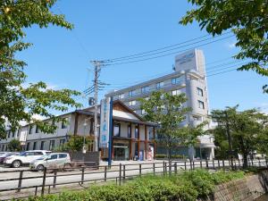 笛吹市Tabist Onsen Hotel Toyo的前面有汽车停放的建筑