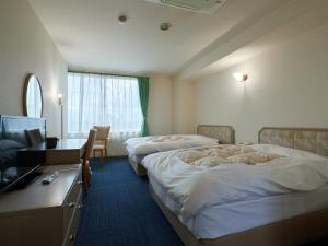 笛吹市Tabist Onsen Hotel Toyo的酒店客房设有两张床、一张桌子和一台电视。