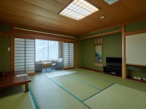 笛吹市Tabist Onsen Hotel Toyo的一间配有平面电视的房间和一间客厅