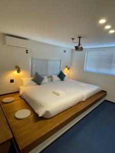 TakagiBridge33 CAFE AND HOSTEL的一间卧室配有一张带两盏灯的大型白色床。