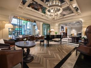 河内GRAND HOTEL du LAC Hanoi的酒店大堂设有钢琴和桌椅