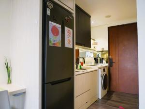 巴淡岛中心Meisterstadt Pollux Habibie的厨房配有带贴纸的黑色冰箱