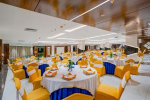 ĀsansolPayel Inn的一个带桌子和黄色椅子的大型宴会厅