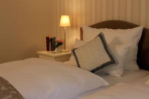 利普施塔特豪斯格美尔旅馆的一张带白色枕头的床和一张带台灯的桌子