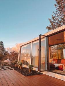 哈莱伊瓦Modern Off Grid Tiny Home!的一座带玻璃墙和木甲板的房子