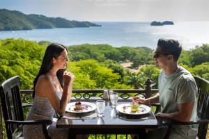 普拉亚埃尔莫萨Villas Sol Beach Resort - All Inclusive的坐在餐桌旁吃食物的男人和女人