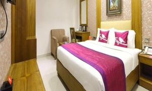 钦奈FabHotel Prime The Vijay Park的卧室配有一张带粉红色枕头的大床