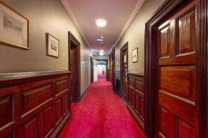 伦敦瑞士小屋朝圣者酒店的走廊上设有木门和红地毯