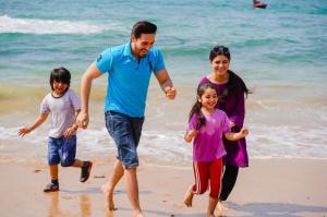 卡拉奇Destination Beach Hotel by Dreamworld的一名男子和两名儿童在海滩上跑