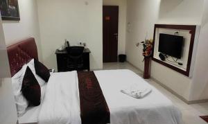 KharadiFabHotel Prime Finesse的一间卧室配有一张大床和电视