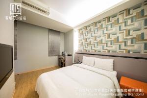 台中市Unique Hotel 黃埔75旅店 的卧室配有一张白色大床和一堵墙