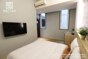 台中市Unique Hotel 黃埔75旅店 的一间卧室配有一张床和一台平面电视