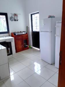 雅温得Pauline的厨房铺有白色瓷砖地板,配有白色冰箱。